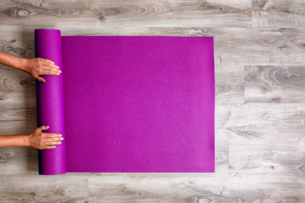 Woman rolling her Yoga mat after a workout - top view